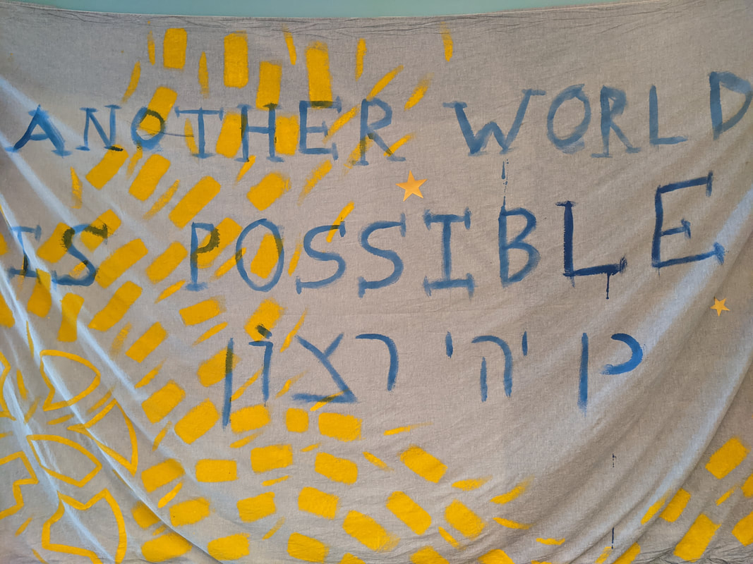 a white tapestry with bright yellow designs, and the painted blue text 